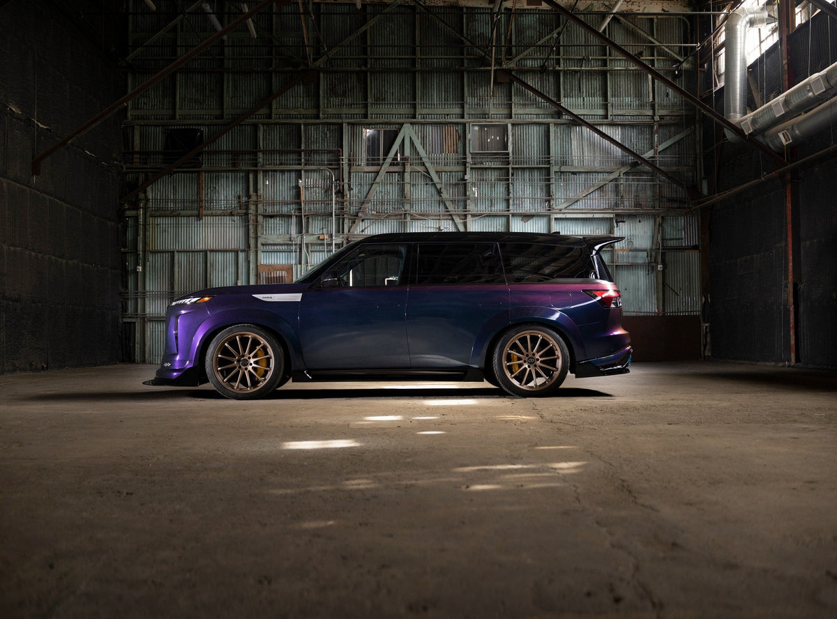 INFINITI QX80 R-Spec side profile in a warehouse, showing the wide-body kit